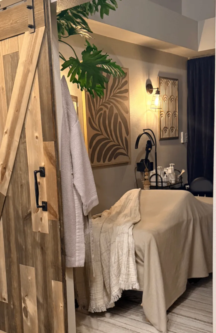 Pure Skin Esthetic treatment room with a massage bed, wood door, and warm lighting